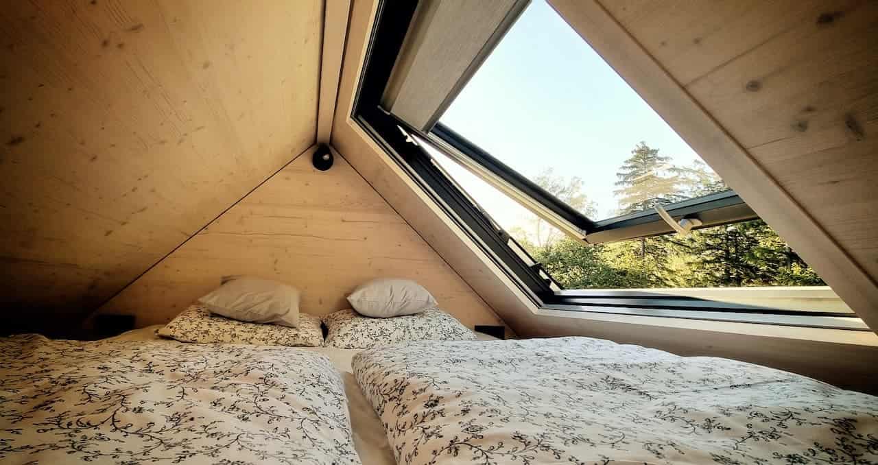 Sleeping loft in tiny house Hutka — skylight with a view